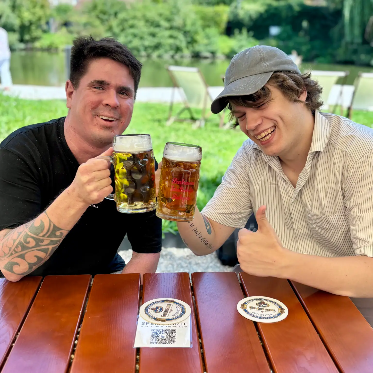 Roland und Benny stoßen lachend an mit zwei vollen Gläsern
